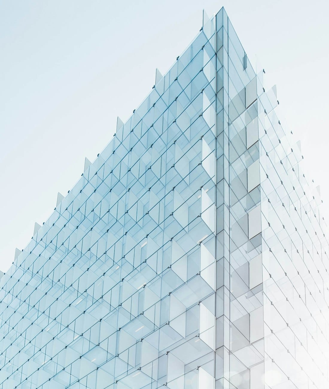 Gläserne Bürofassade im Morgenlicht, von unten fotografiert